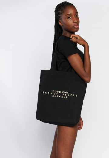 Tote Bag in Schwarz in praktischer Größe und langen Henkeln. Mit beigem Motiv-Druck auf der Vorderseite und Logo-Druck auf der Rückseite. Ein Statement-Piece für Sustaibabilty.  REER3 - Good for Planet, People, Animals